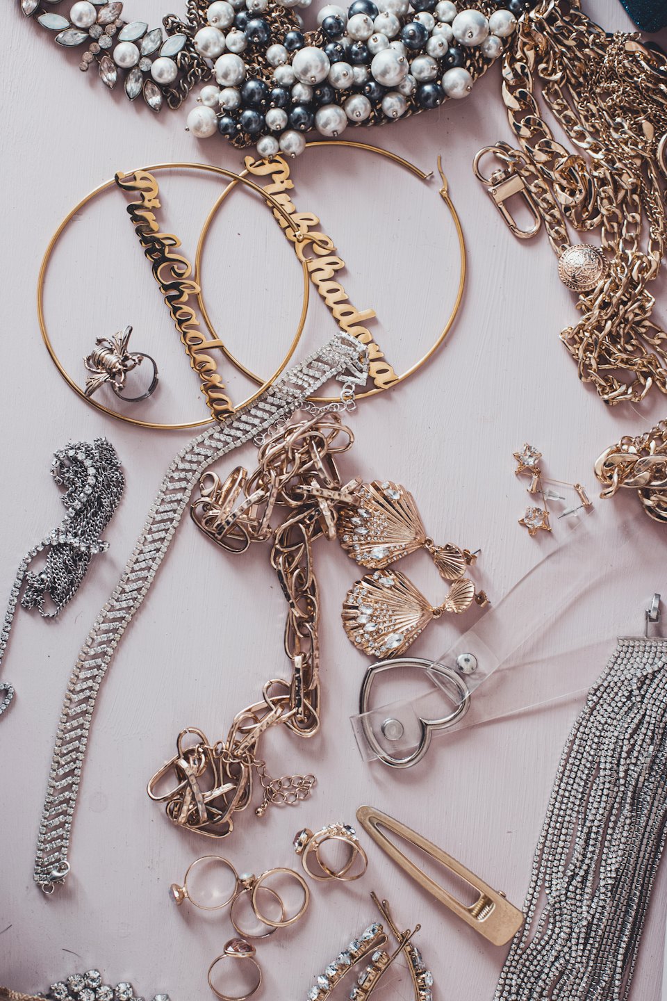 Gold and silver jewelry and hair clip on pink wood.